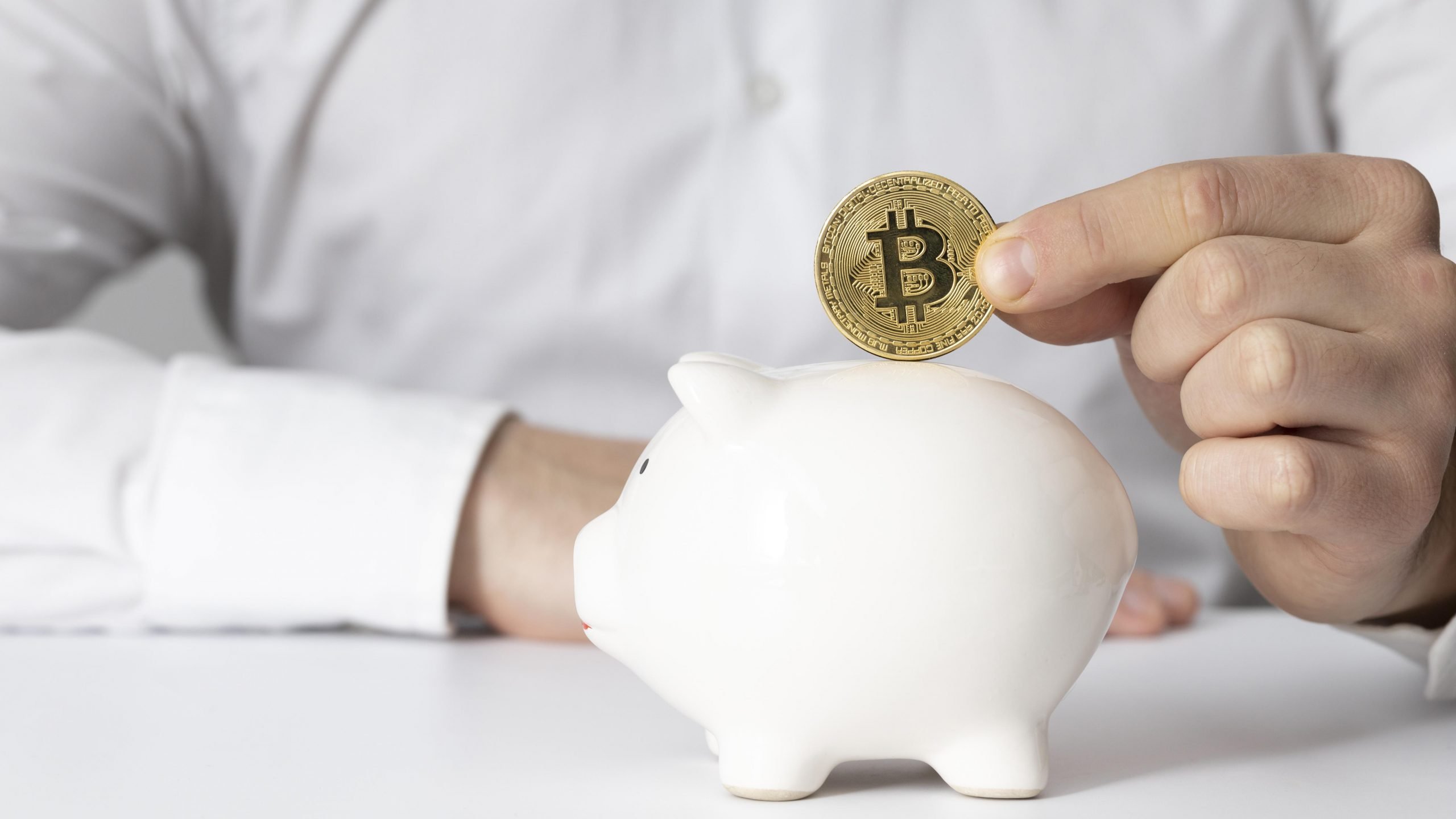 Man inserting bitcoin on piggy bank