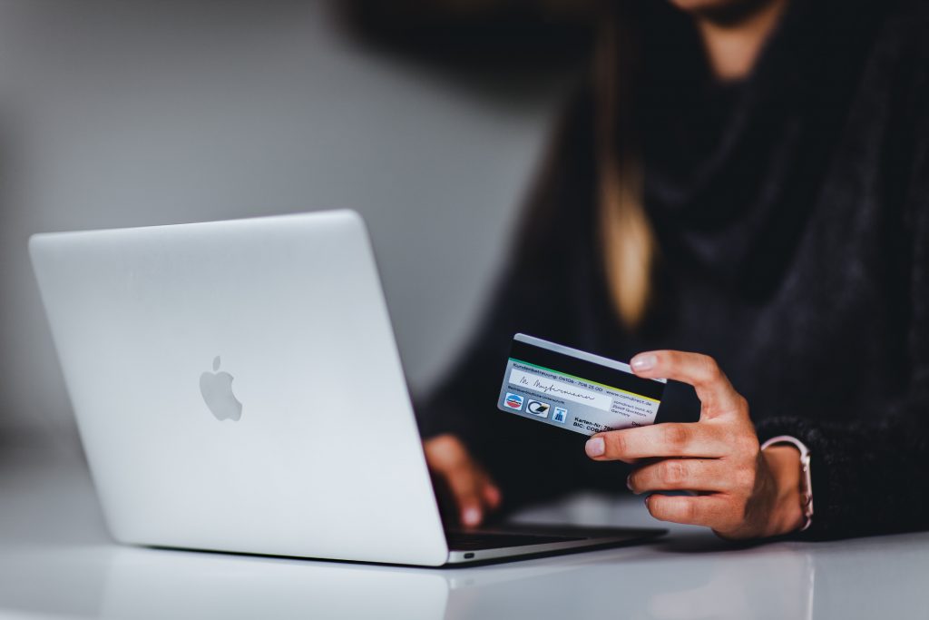 Mulher com cartão e notebook, fazendo compras online.