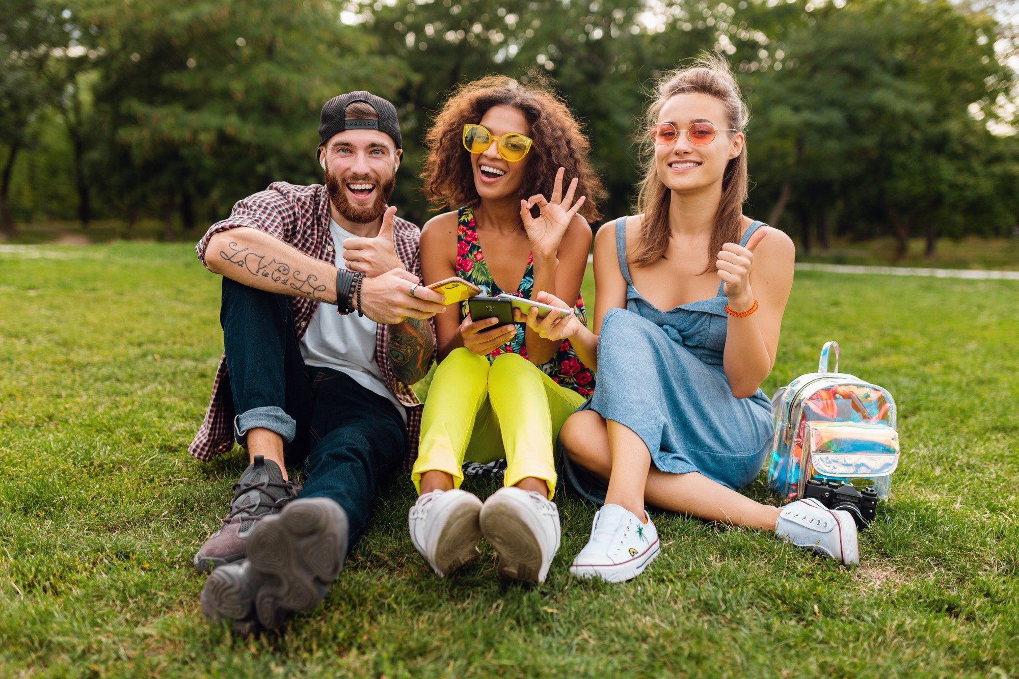 happy young friends using smartphones