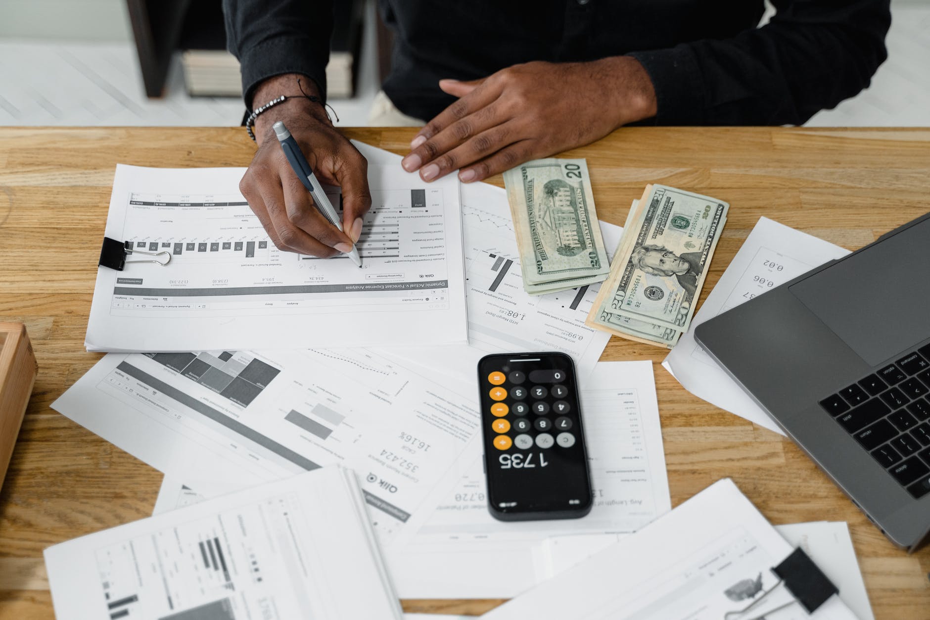 Man writing on paper; dollar bills, calculator