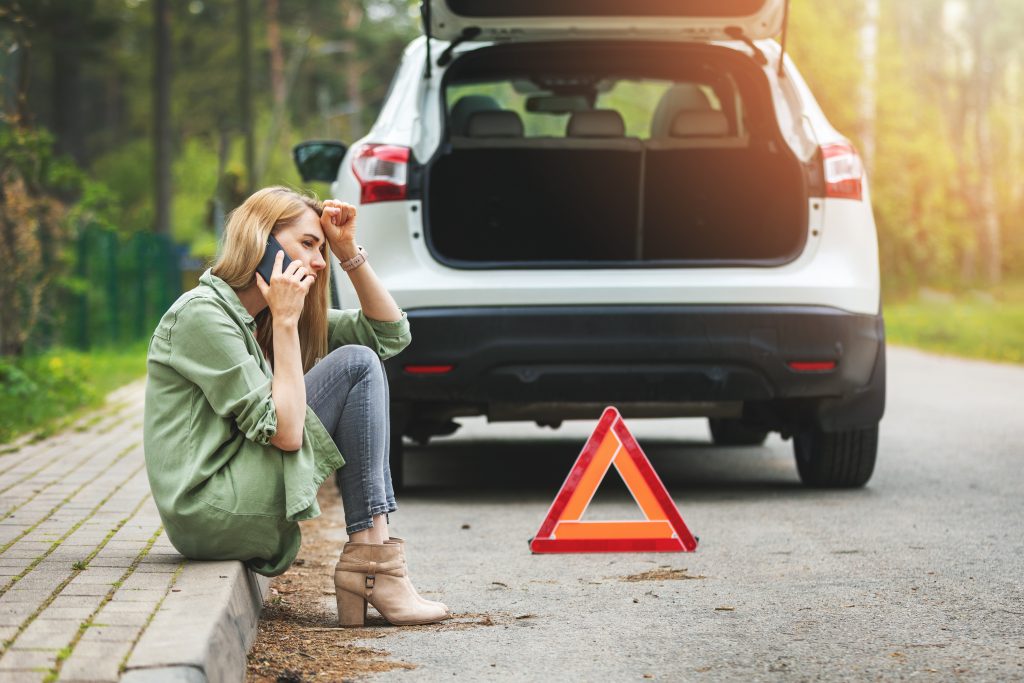 woman is sitting on the side of the road and calling for help be