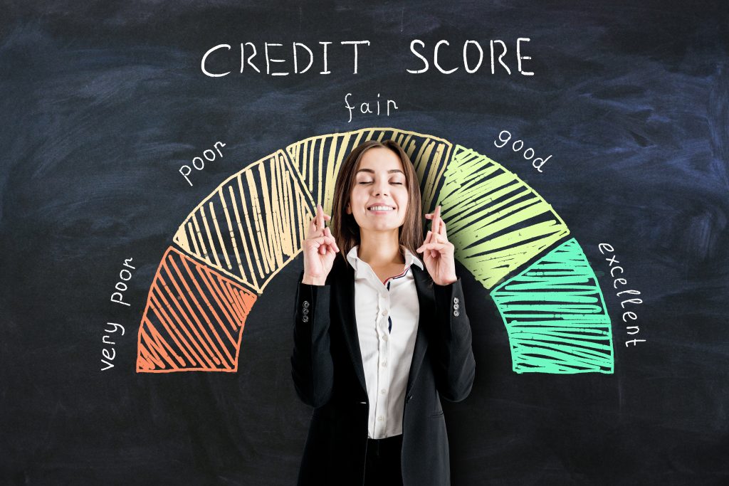 Bank loan concept with businesswoman crossing her fingers on blackboard background with credit score scale.