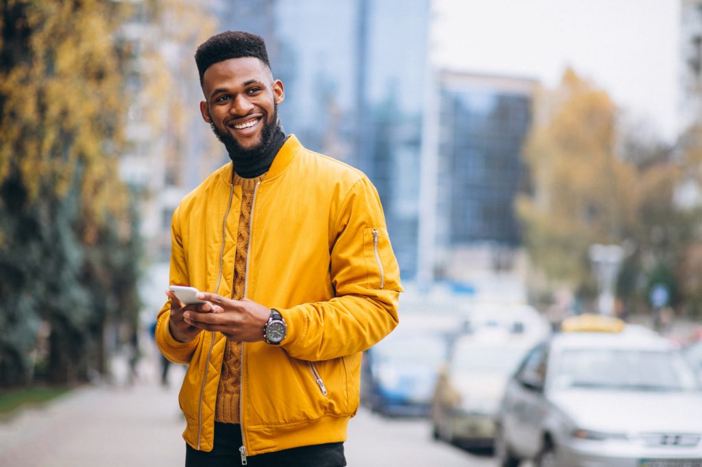 smiling man holding cellphone on the street