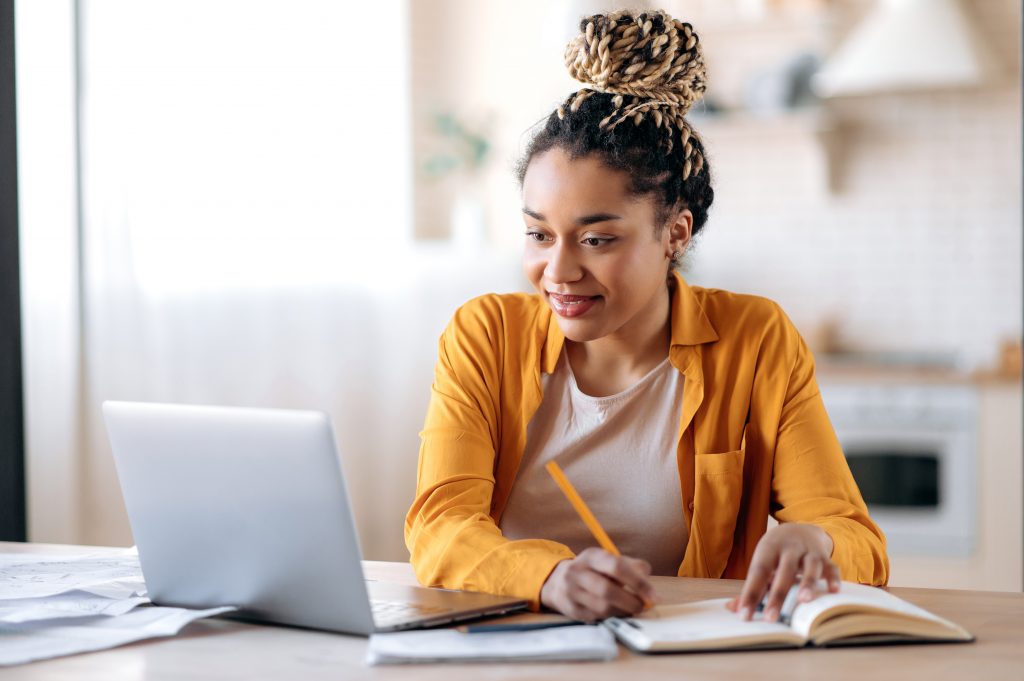 woman making notes looking at computer