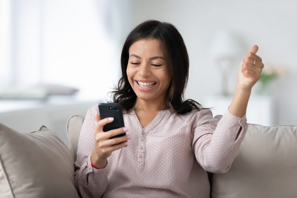 Excited happy African American girl with cell phone