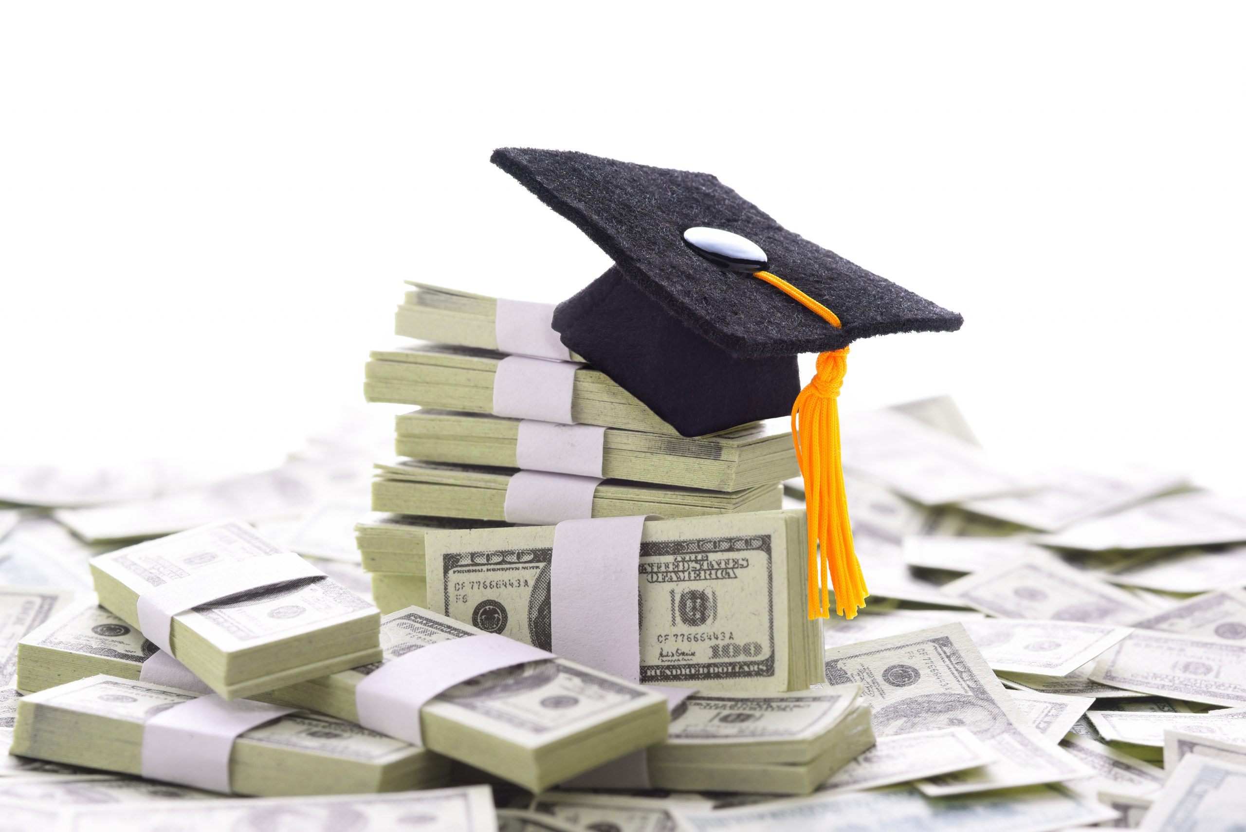 Mortarboard on a pile of money representing the high cost of higher education and bribery