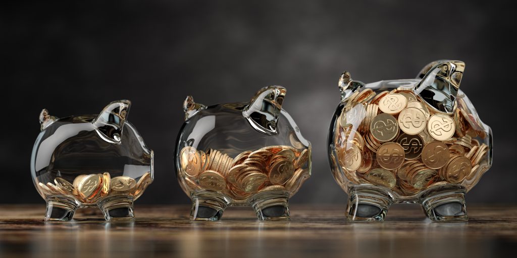 Glass piggy bank of different size with golden coins. Fiinancial