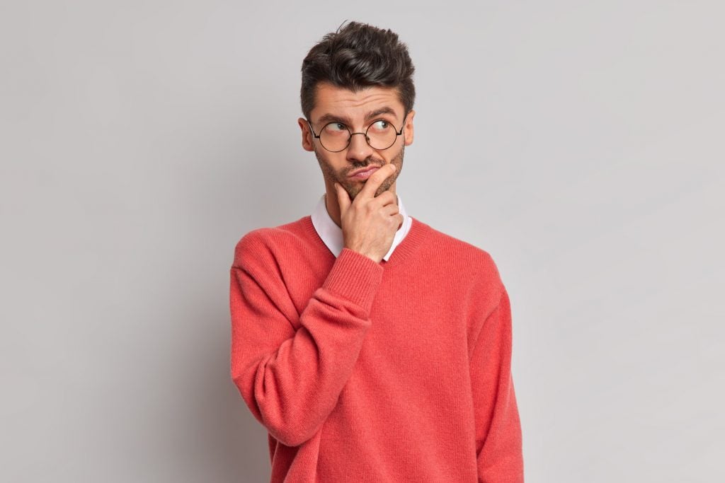 thoughtful man holds chin