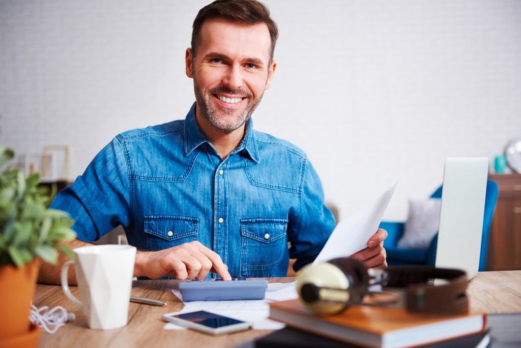 portrait-smiling-man-calculating-his-monthly-expenses