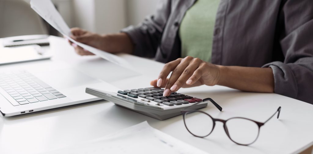 Woman accountant using calculator and computer in office panoram