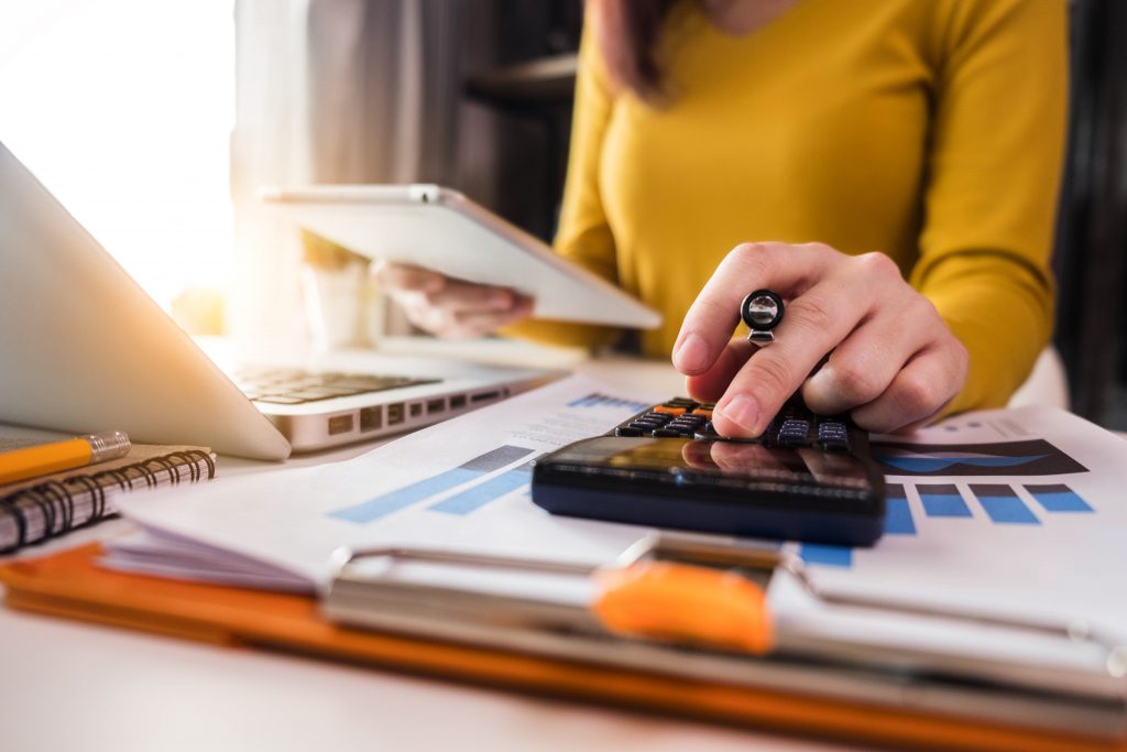 Business women using calculator with a computer