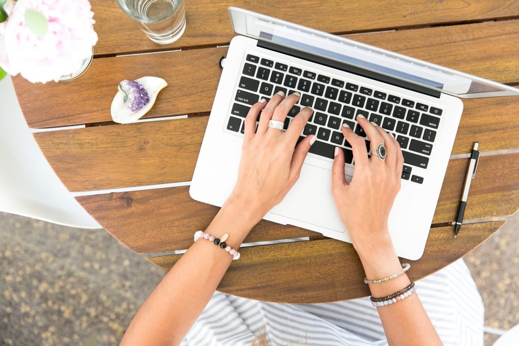 top view of female hands in a laptop on a wood table