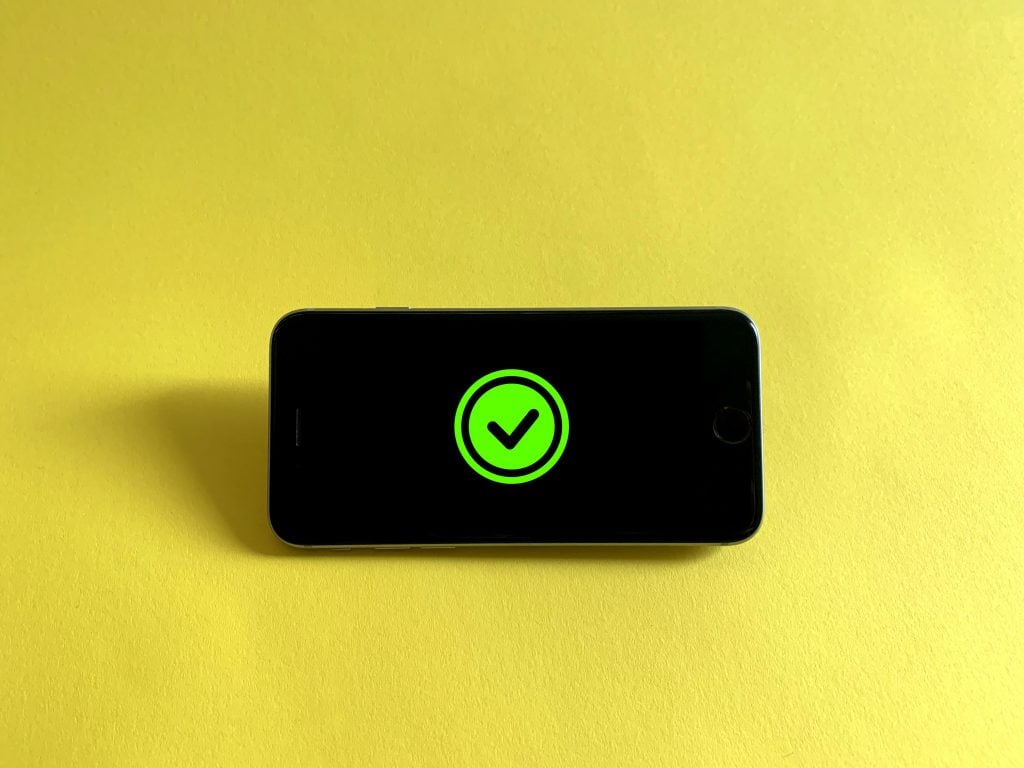Cell phone on a yellow background, showring a "donE" symbol on the screen