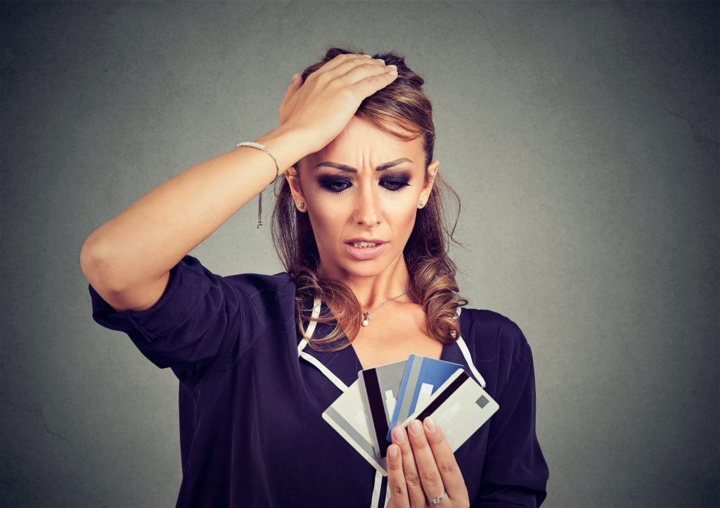 Confused stressed woman looking at too many credit cards