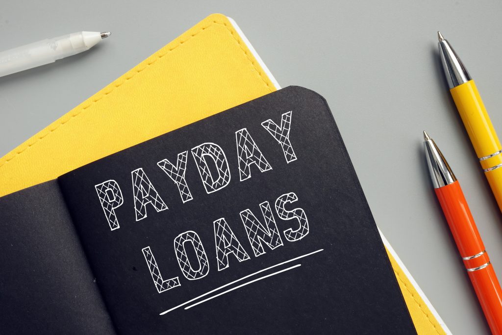 Financial concept meaning PAYDAY LOANS with phrase on the page. A payday loan is cash advance offered to help you get to your next paycheck