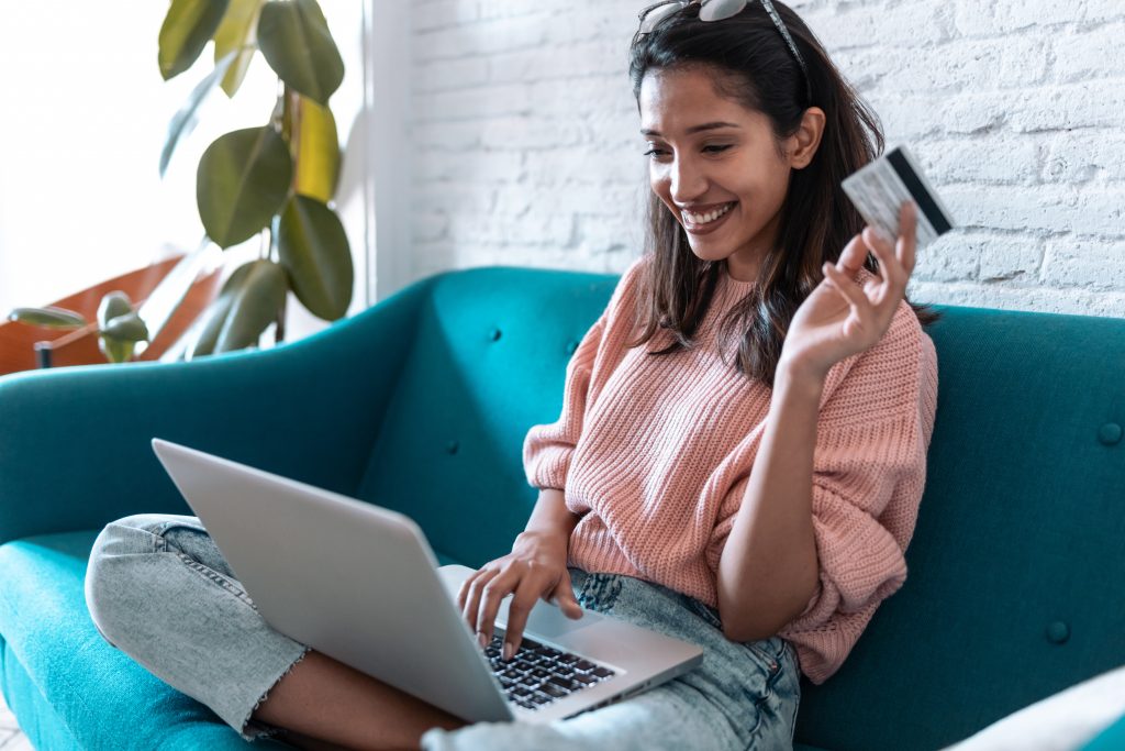 Pretty young woman shopping online with credit card and laptop w