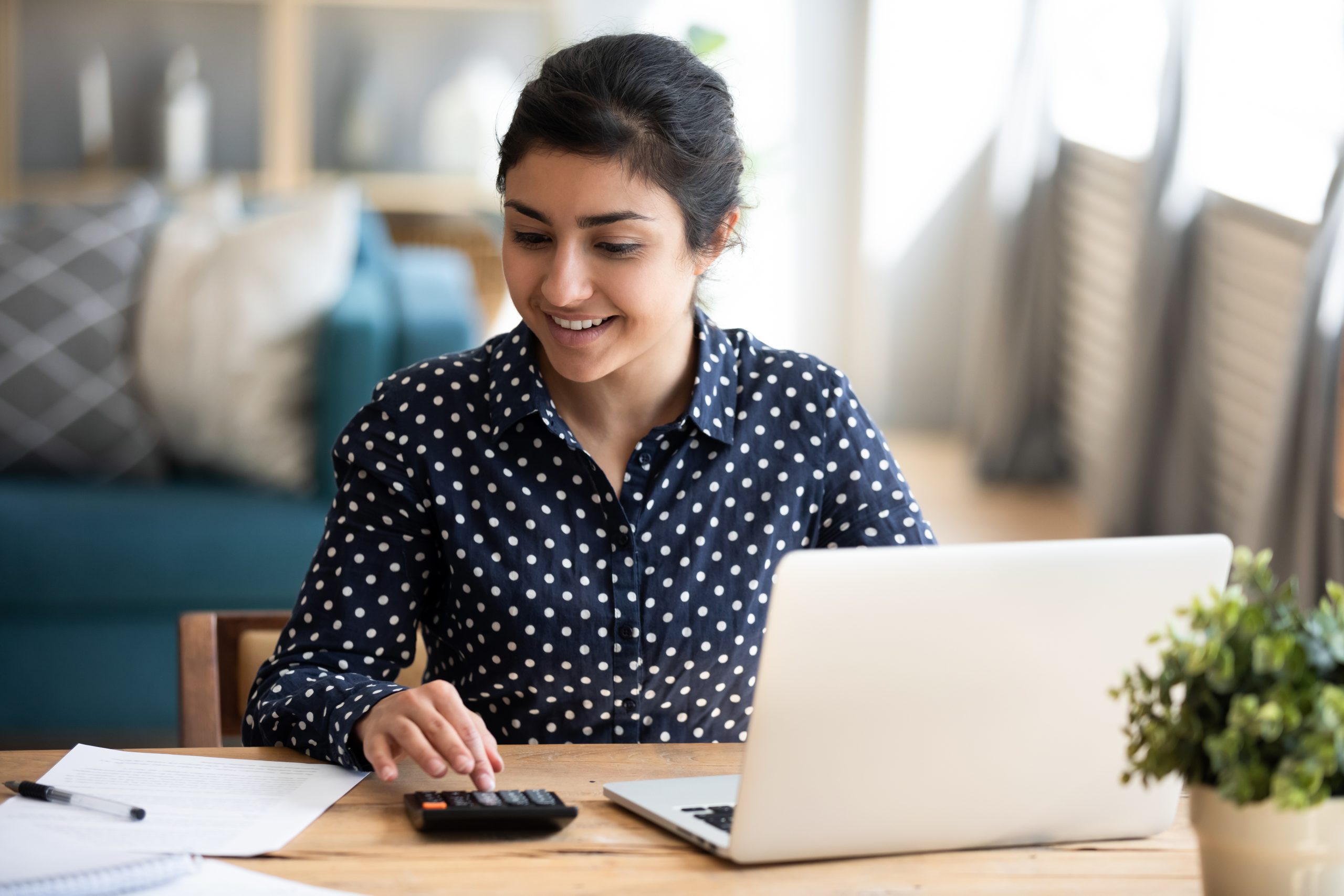 Millennial indian woman paying bills on laptop online