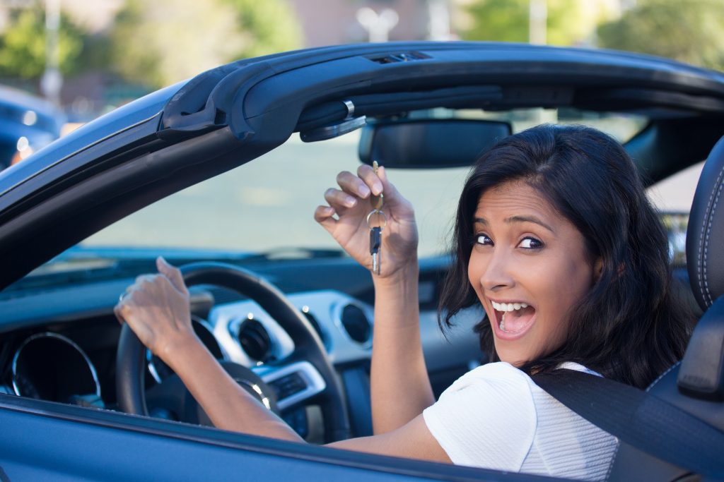 Closeup portrait, young cheerful, joyful, smiling, gorgeous woman holding up keys to her first new sports car. Customer satisfaction