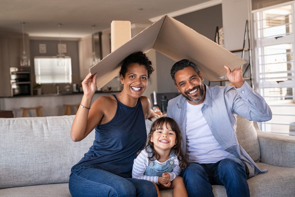 Happy multiethnic family with child holding cardboard roof