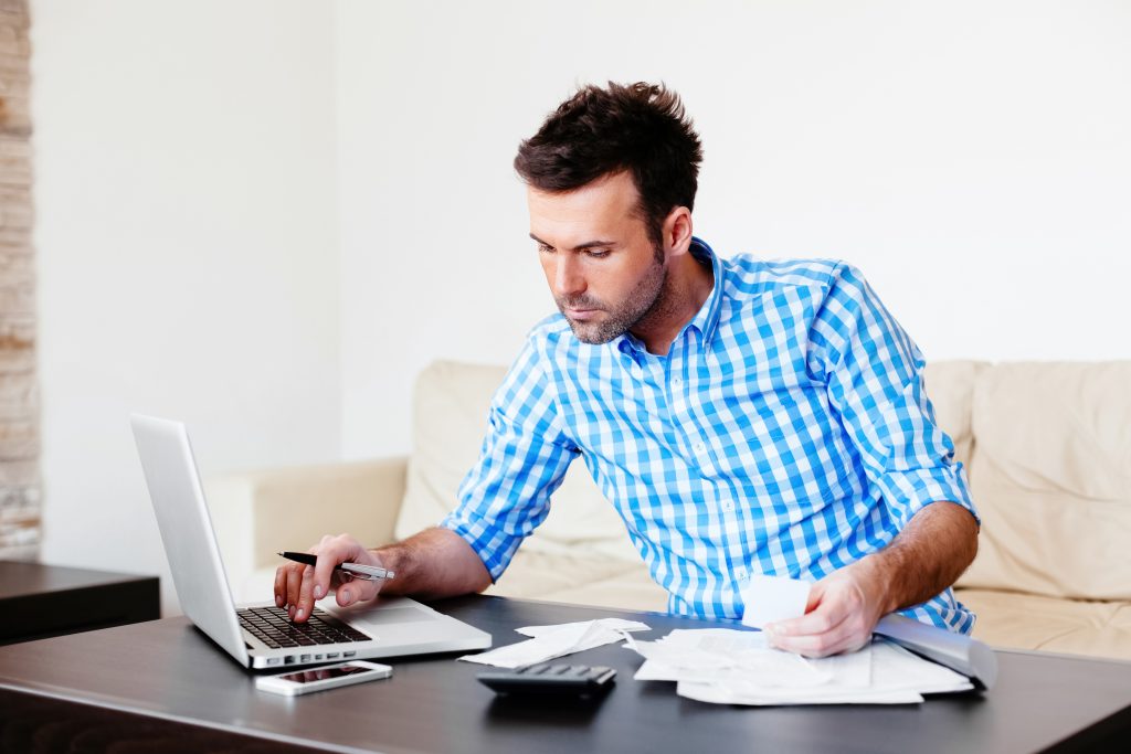 Young man paying bills with his laptop