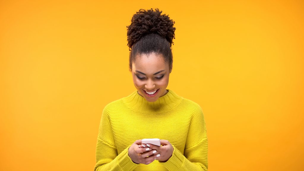 Smiling African-American woman chatting on smartphone, modern technology, app