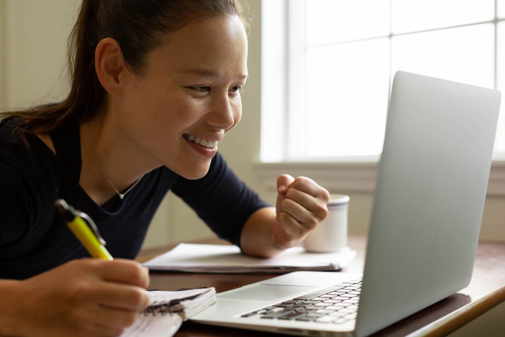 Woman is happy working from home on a project inspired on the progress she is making.