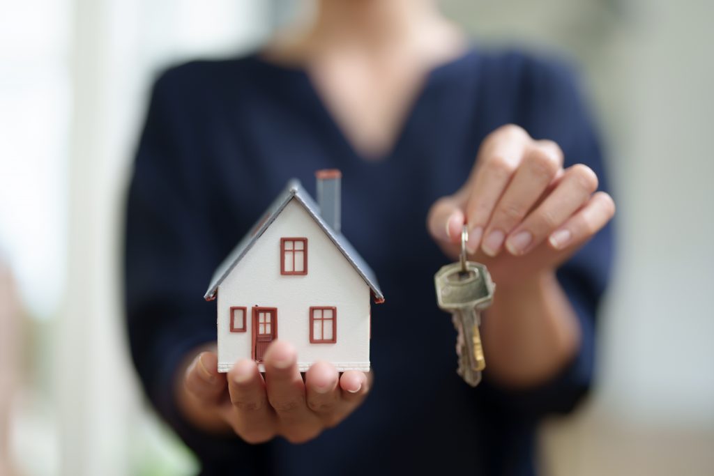 Asian female bank employee handing over a house and keys to a client after signing a contract on paperwork