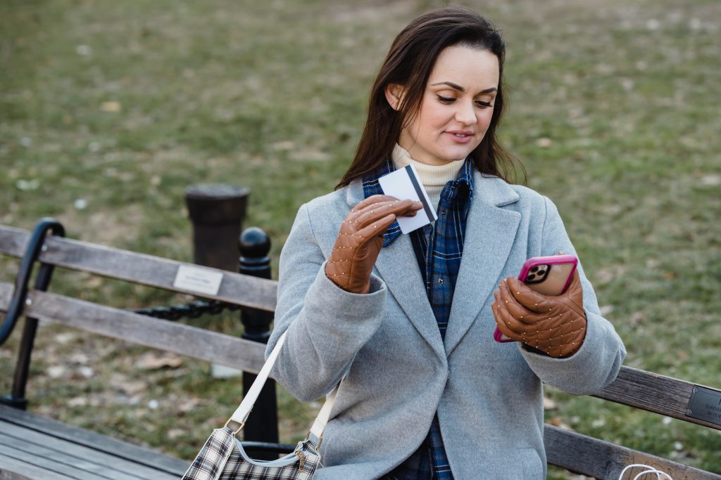 Woman using holding a card, and checking the cell phone
