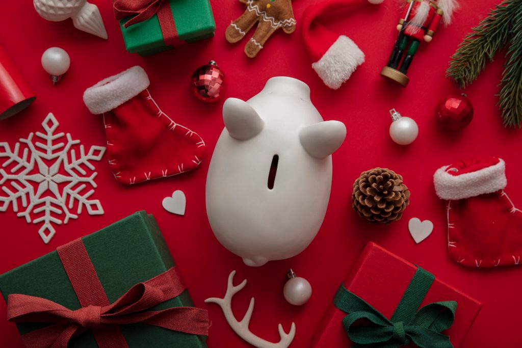 Festive Christmas financial savings concept. White piggy bank money box with presents and decorations