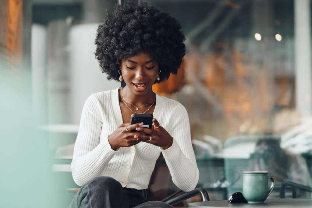 Portrait of a beautiful young african woman using her cellphone in a cafe