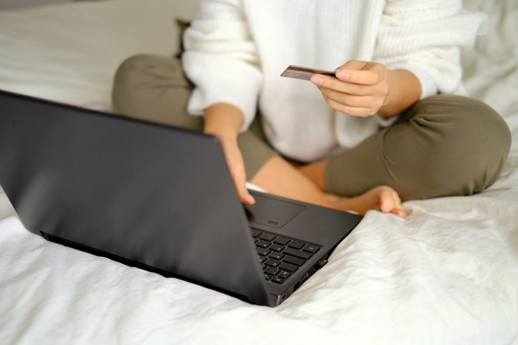unrecognizable women doing online shopping on the bed. Woman shopping online with credit card and laptop computer at home