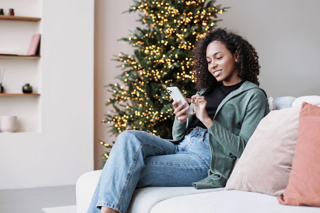 Young woman using smartphone at home during Christmas holiday, S