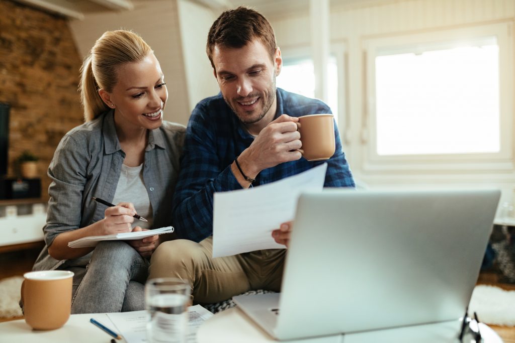 Happy couple making their home budget while going through financ