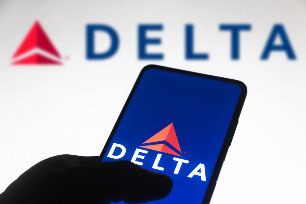 In this photo illustration the Delta Air Lines logo is seen displayed on a smartphone screen and in the background