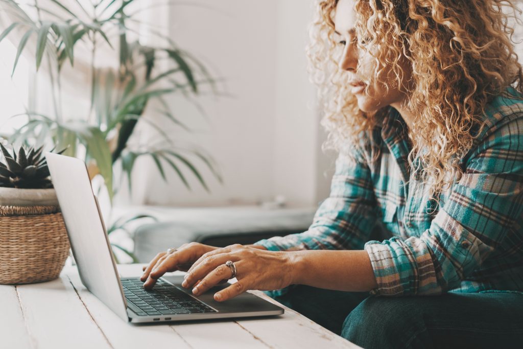 People working on computer at home. One woman write and use lapt