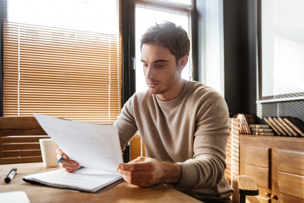 Attractive young man in office working with documents.