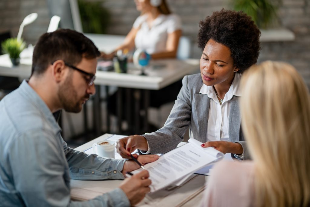 African American bank manager and a couple signing a contract in