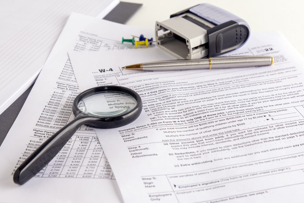 blank form W-4, magnifier and a pen on table. tax season