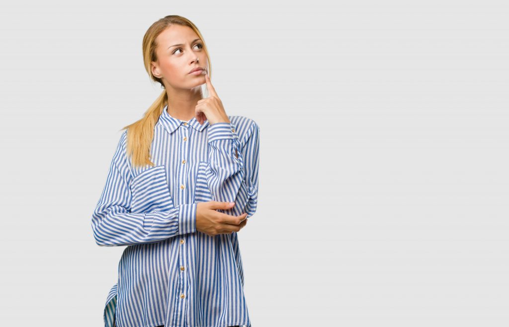 Portrait of a young pretty blonde woman thinking and looking up, confused about an idea, would be trying to find a solution