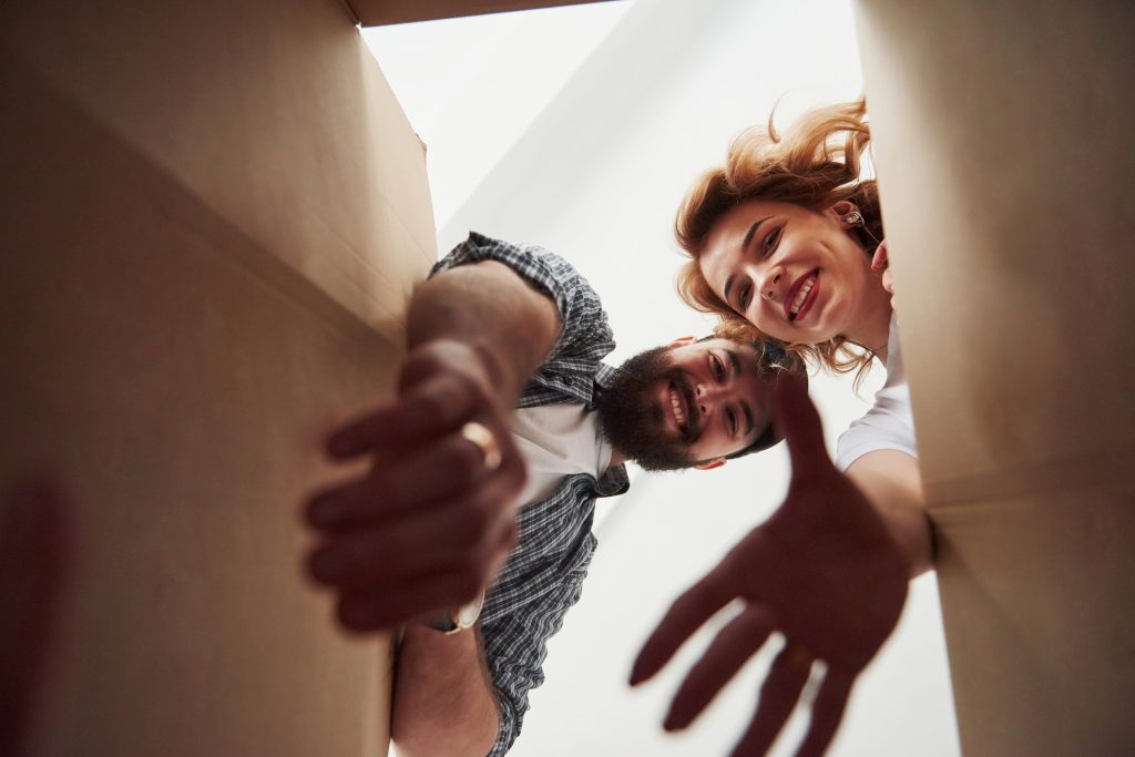 Taking clothes from the box. Happy couple together in their new house. Conception of moving