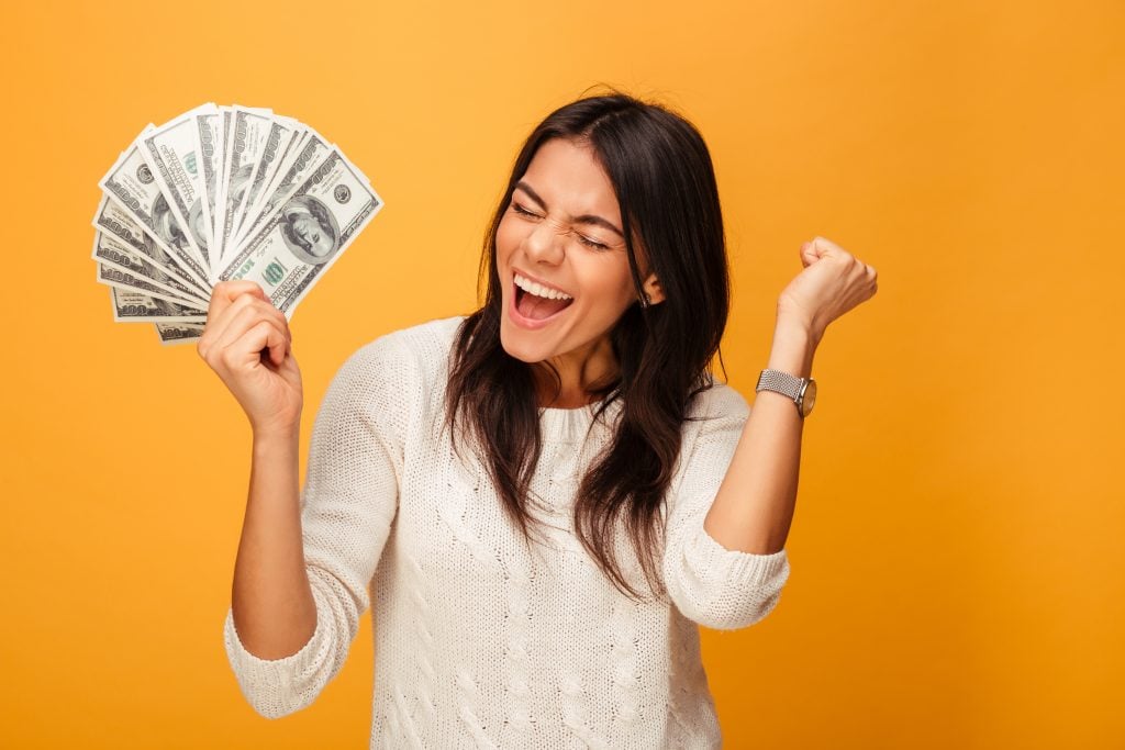Portrait of a cheerful young woman holding money