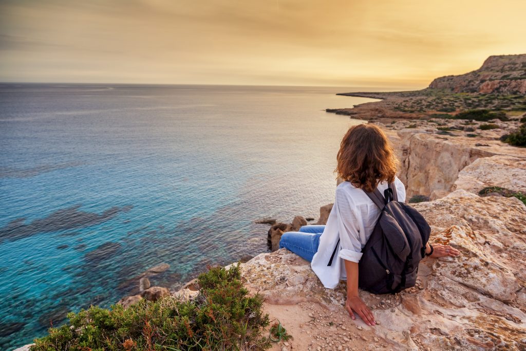 A stylish young woman traveler watches a beautiful sunset on the