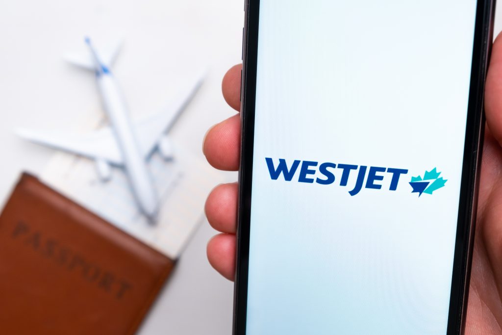 Westjet Airline app on a smartphone screen with a plane and passport on the background. The concept of travel app. November 2021, San Francisco, USA.