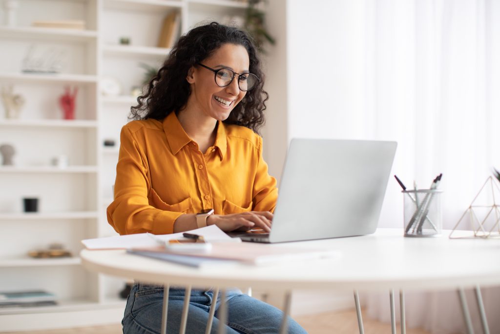 Happy Middle Eastern Businesswoman Using Laptop Sitting At Workplace