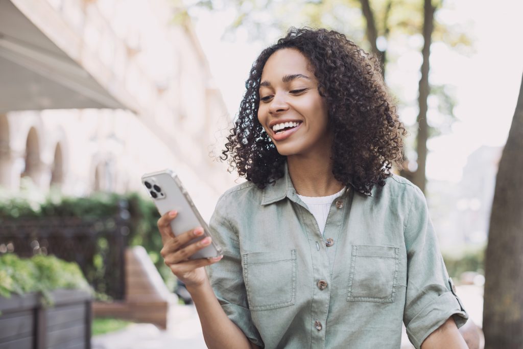 Young beautiful woman using smartphone in a city. Smiling studen