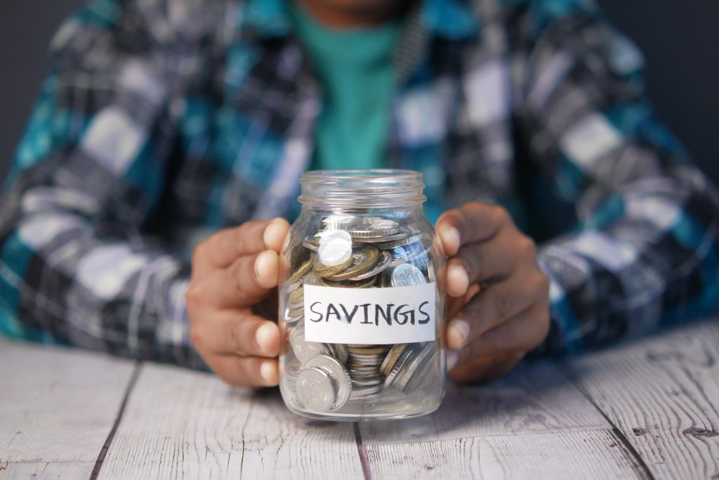 child boy hand hold a saving coins jar