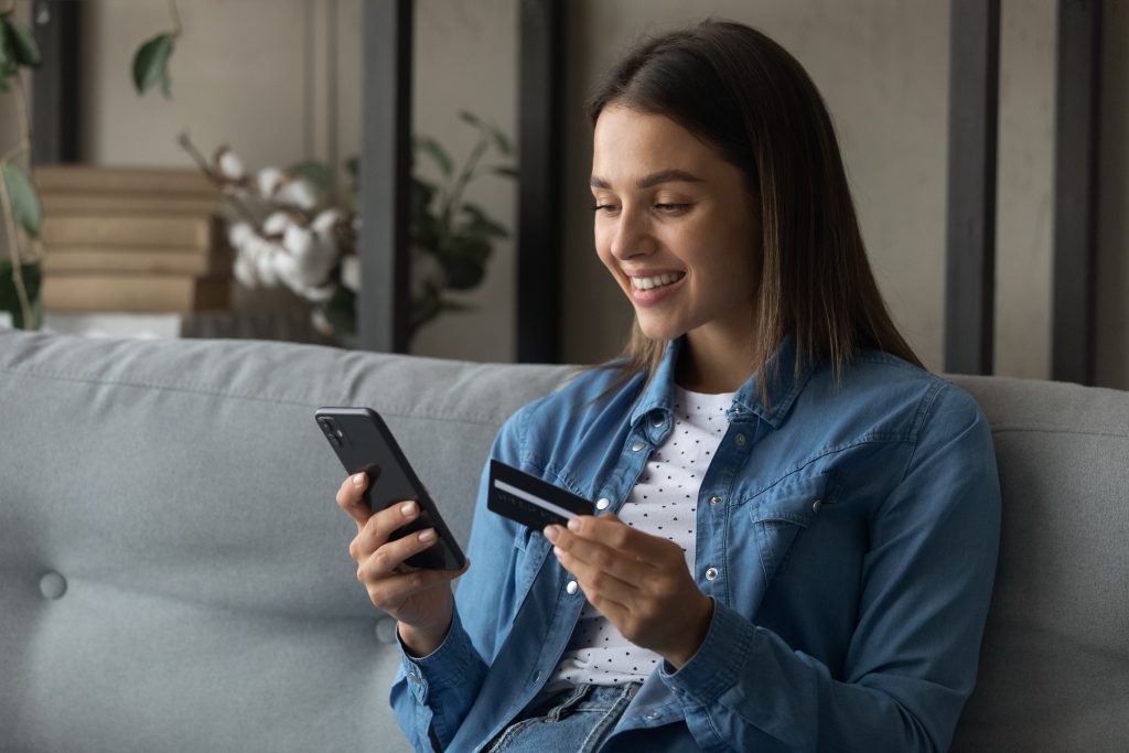 Happy young female use bank card to buy goods online