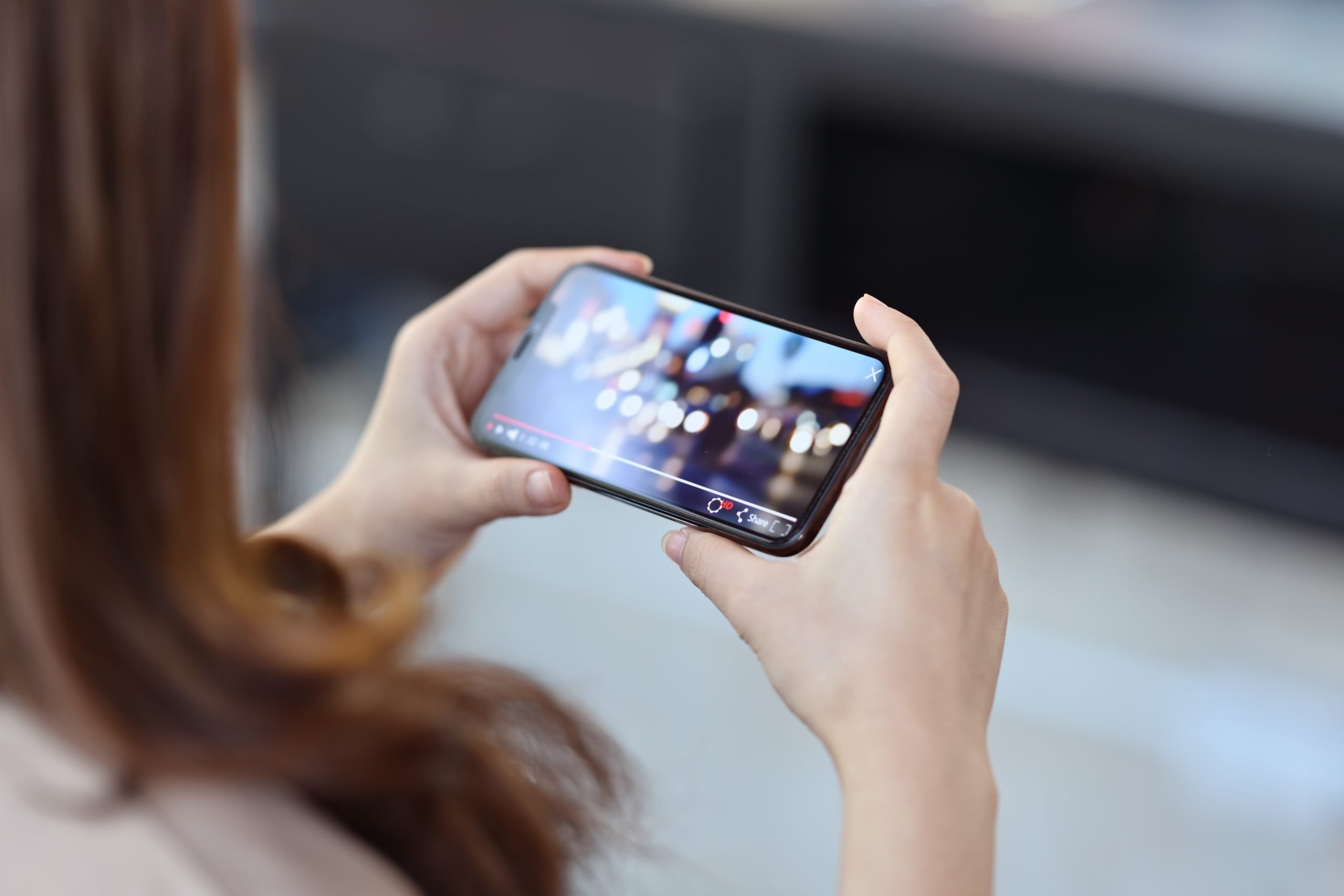 Cropped shot of female hand holding mobile phone playing video stream online