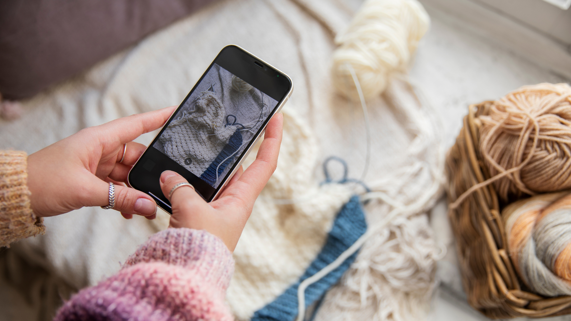 close up hands holding smartphone taking picture of crochet