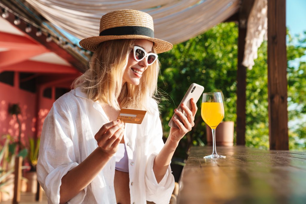 Image of joyful nice woman holding credit card and using cellphone